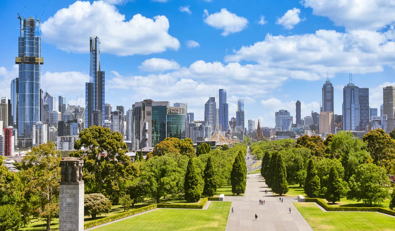 People exploring a wide-open park near the war memorial in sunny Melbourne, Australia